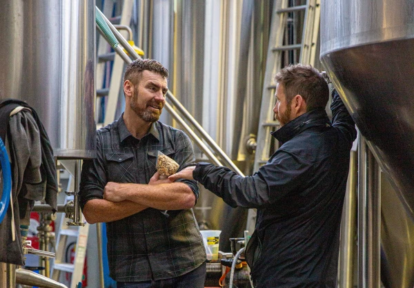 2 men italking  whilst stanging amongst bread making machinery 