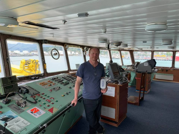 Dudley Jackson on the bridge of a boat looking at camera