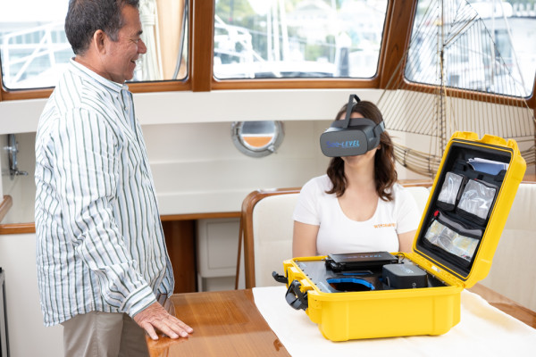 standing man watching a seated woman testing See-LEVEL’s VR headset